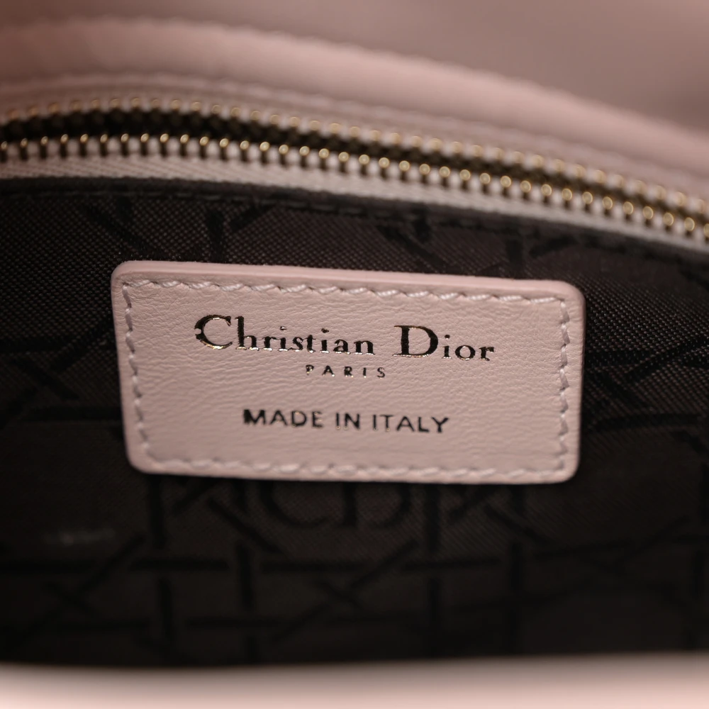 Close-up of the signature charms and gold-tone hardware on the D!0r Light Pink Cannage lambskin small bag