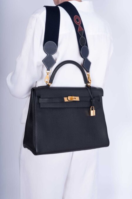 Model carrying the Herme$ Kelly Retourne 32 Black Togo Leather with gold hardware