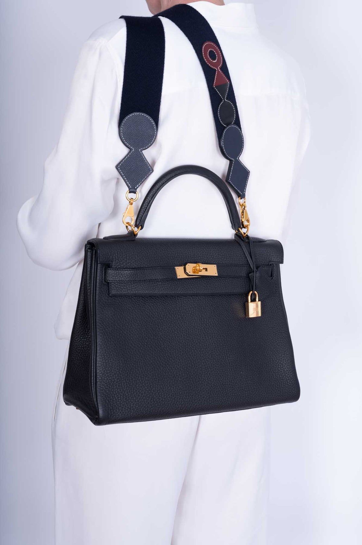 Model carrying the Herme$ Kelly Retourne 32 Black Togo Leather with gold hardware