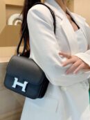 Model carrying the Herme$ Epsom Constance 18 in Black calf leather with gold hardware