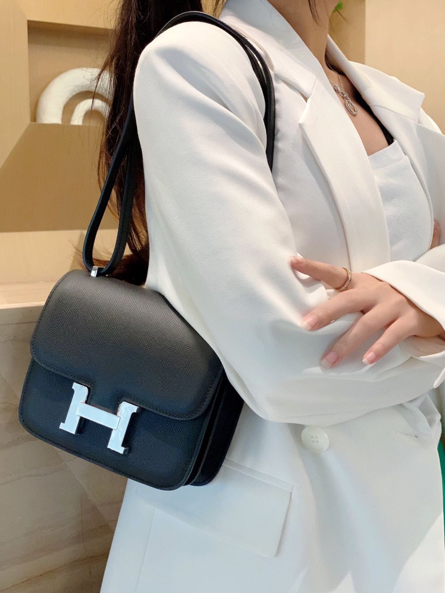 Model carrying the Herme$ Epsom Constance 18 in Black calf leather with gold hardware