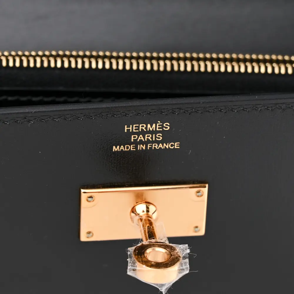 Close-up of the Herme$ Kelly turn-lock and gold hardware on the Box Leather Kelly Wallet To Go