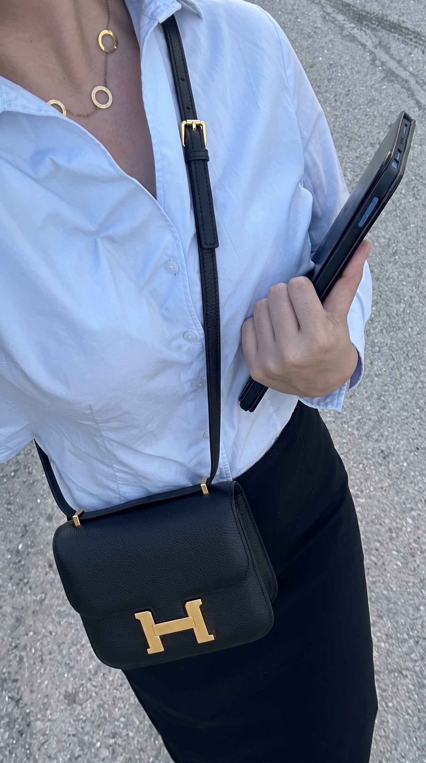 Model carrying the Herme$ Chevre Mysore Constance 18 in Black goatskin leather with gold hardware