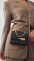 Model carrying the Herme$ Chevre Mysore Mini Verrou Chaine Bag in Black goatskin leather with gold hardware