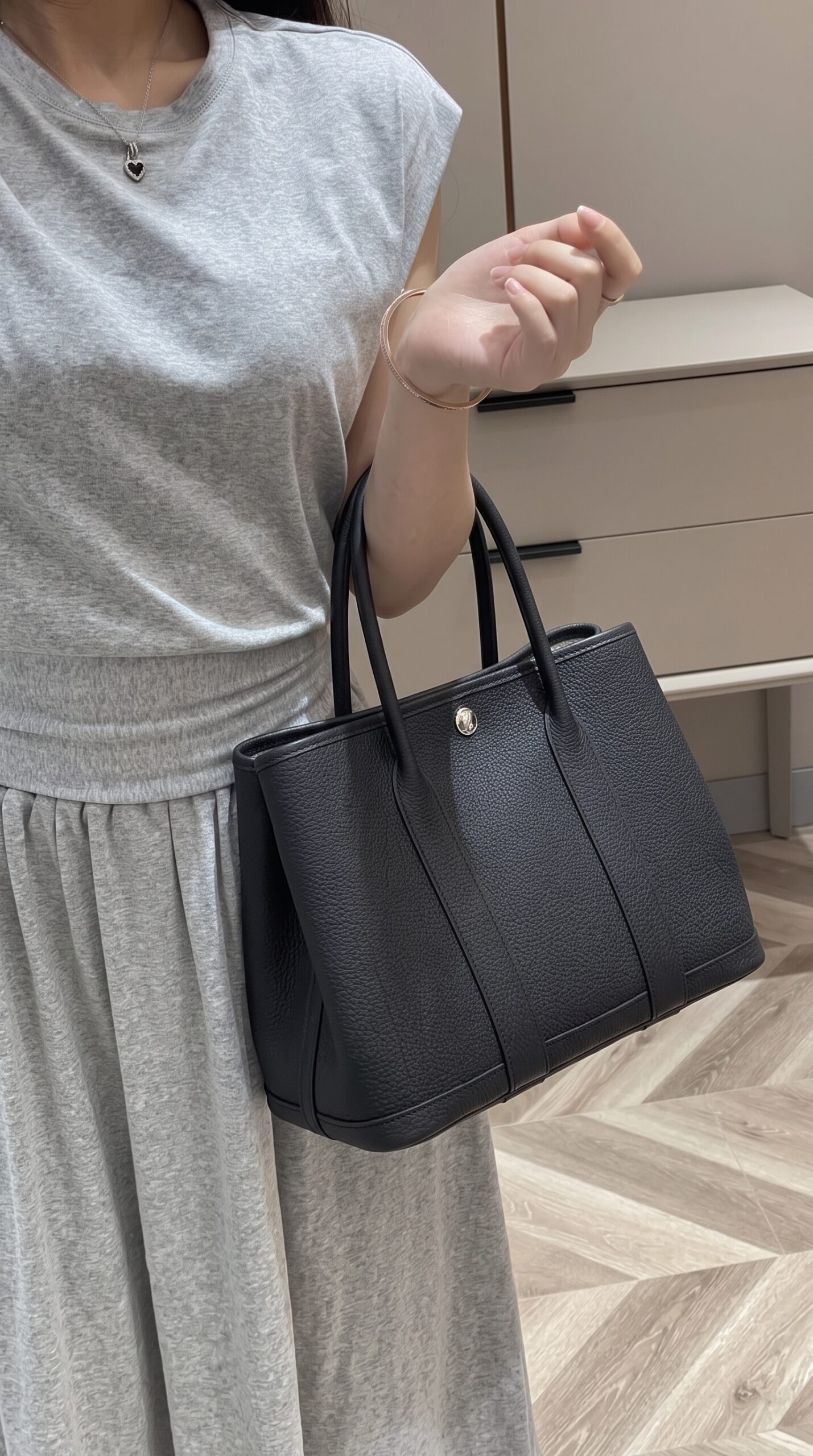Model carrying the Herme$ Negonda Garden Party 30 TPM in black grained leather with Palladium hardware