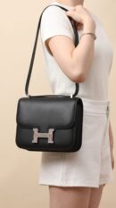 Model carrying the Herme$ Black Ombre Veau Monsieur and Lizard Leather Constance 18 with Palladium silver hardware