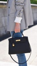 Model carrying the Herme$ Kelly Retourne 28 Black Togo Leatherwith gold hardware