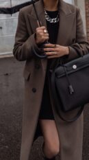 Model carrying the Herme$ Herbag Zip PM 31 Black/Ecru Toile H Vache Hunter Leather with Palladium hardware