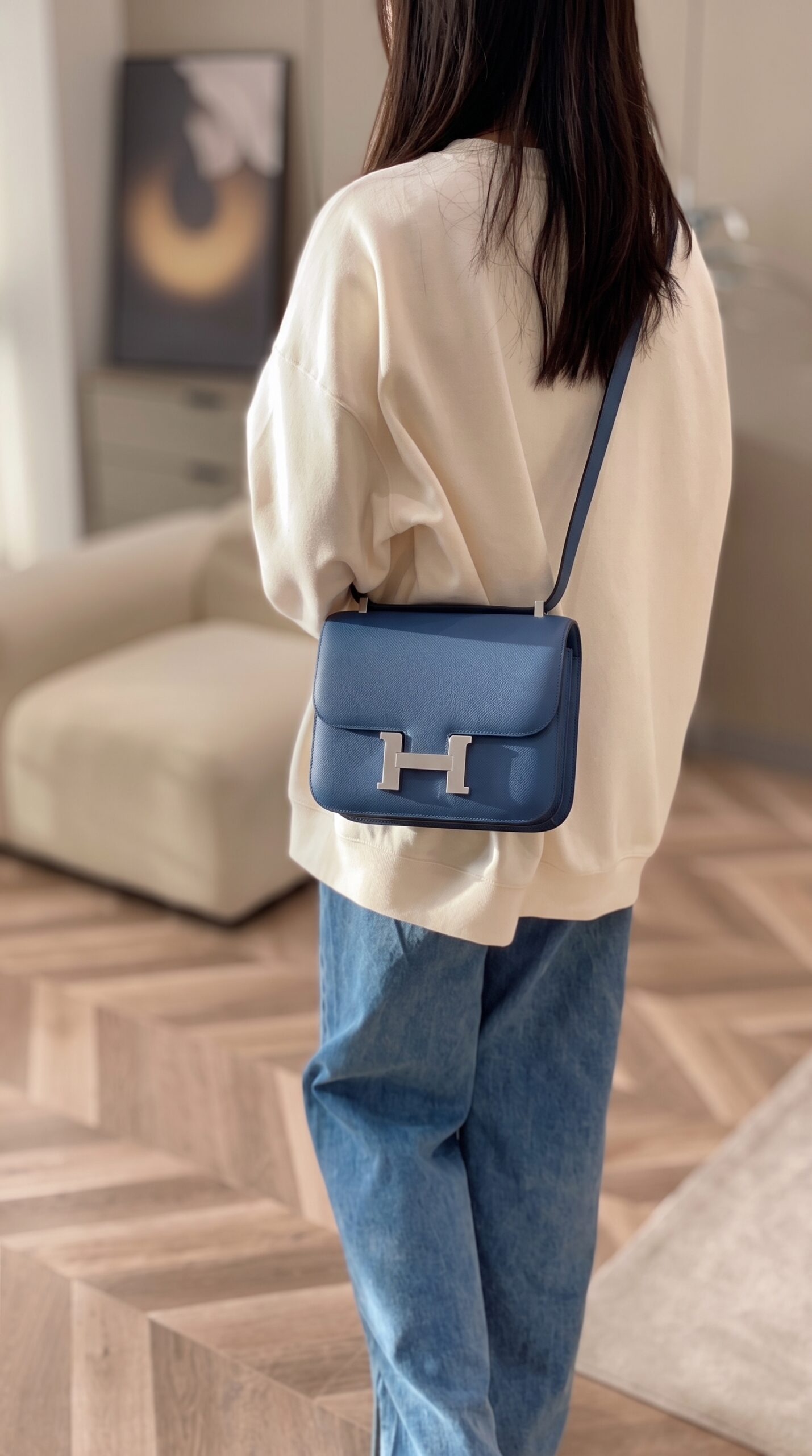Model carrying the Herme$ Constance Verso 24 Bleu Agate Gris Mouette Epsom Leather with Palladium silver hardware
