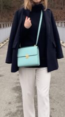 Model carrying the Herme$ Verso Clic 16 Wallet in Bleu Atoll Malachite Epsom Leather with gold hardware