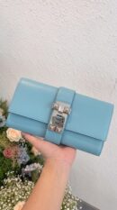 Model carrying the Herme$ Tadelakt Medor 23 Clutch Bleu Atoll Tadelakt Leather with Palladium hardware
