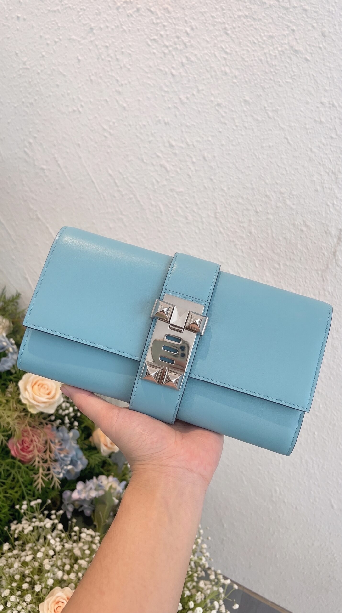 Model carrying the Herme$ Tadelakt Medor 23 Clutch Bleu Atoll Tadelakt Leather with Palladium hardware