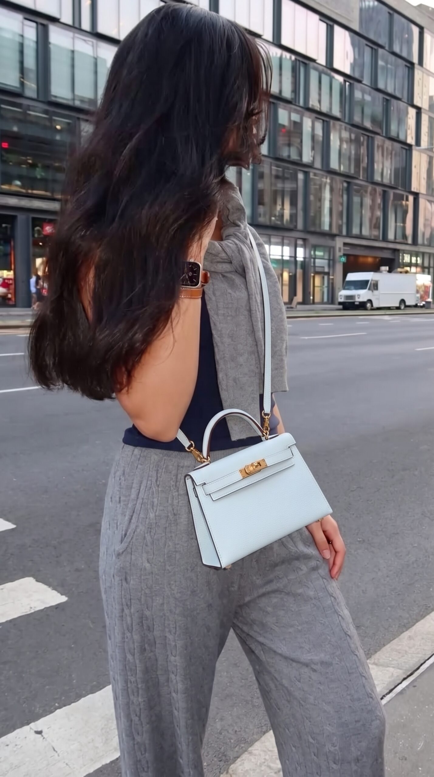 Model carrying the Herme$ Bleu Brume Chèvre Mysore Leather Mini Kelly Sellier 20 with Permabrass hardware