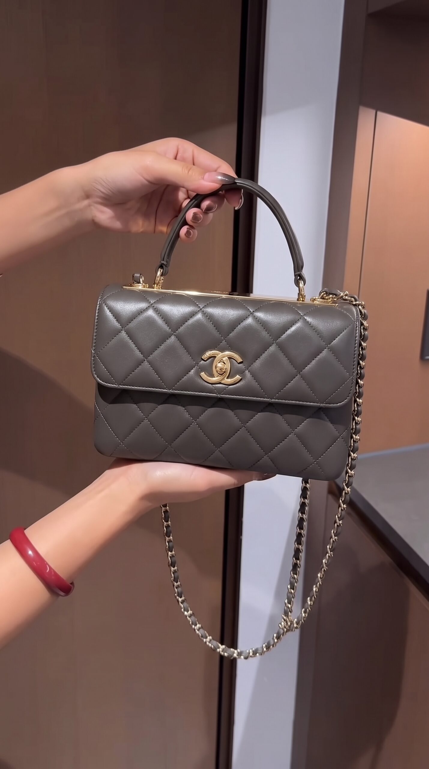 Model carrying the dark khaki quilted lambskin leather Ch@nel Small Trendy CC Flap Dual Handle with gold hardware