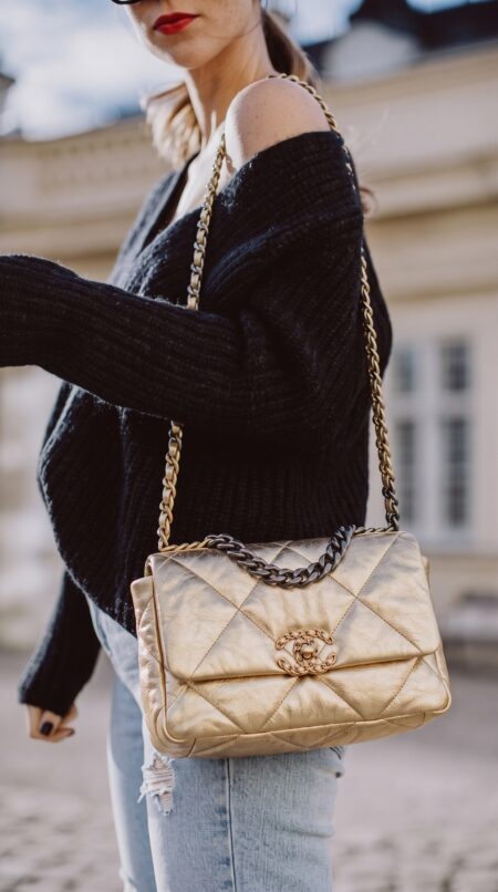 Model carrying the gold metallic lambskin Ch@nel Medium 19 Flap with mixed-metal chain-link strap