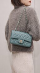 Model carrying the green lambskin ch@nel Mini Rectangular Flap with polished gold chain strap