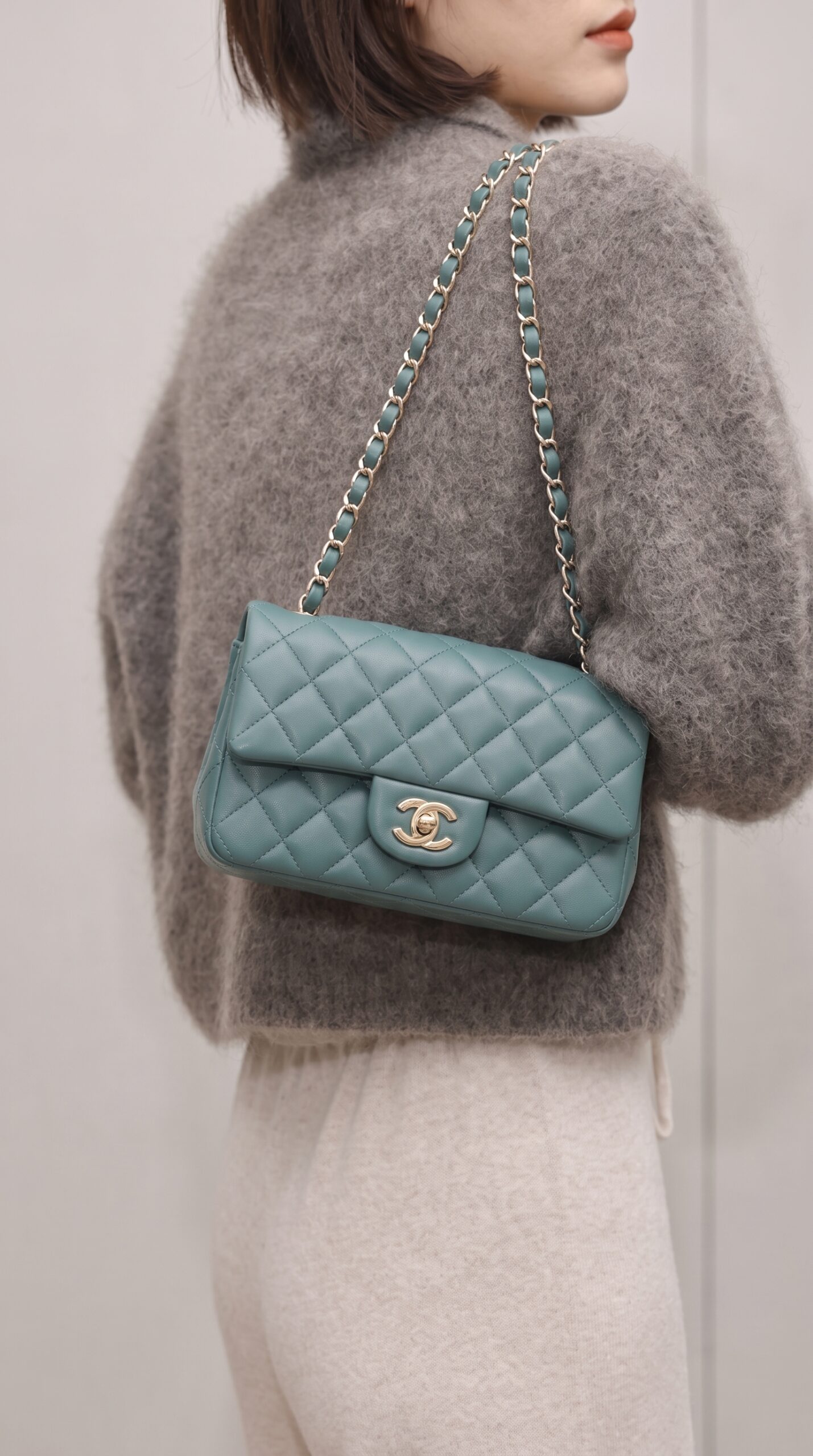 Model carrying the green lambskin ch@nel Mini Rectangular Flap with polished gold chain strap