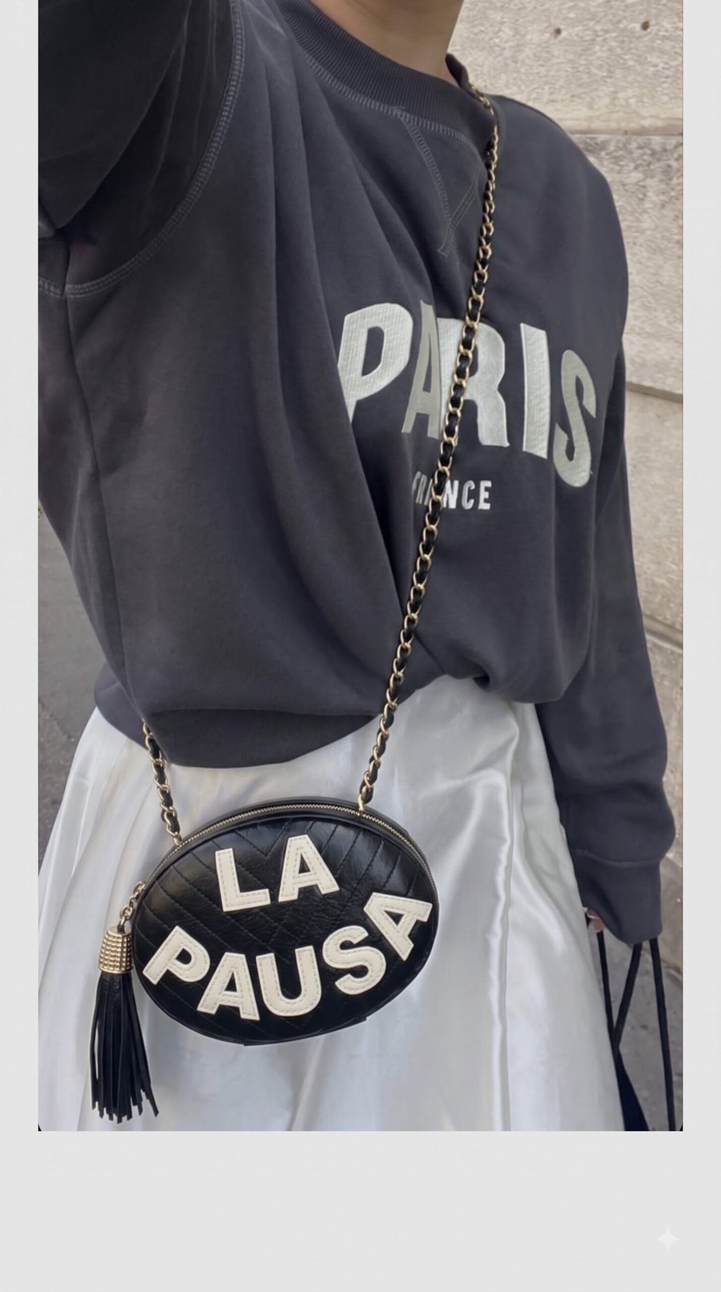 Model carrying the black lambskin Ch@nel La Pausa Tassel Clutch with light gold chain strap