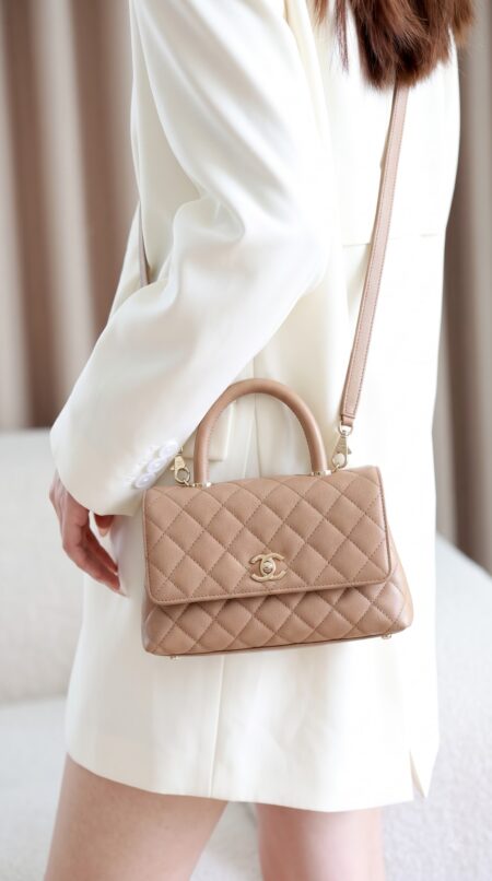Model carrying the brown caviar leather Ch@nel Mini Coco Handle Flap with gold chain strap