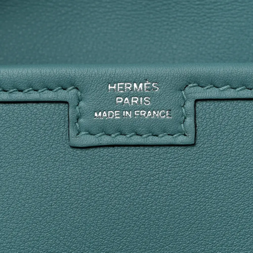 Close-up of the signature H tab closure on the Herme$ Bleu Atoll Swift Leather Jige Elan 29 Clutch