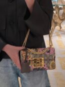 Model carrying the GG Supreme Monogram Bengal Small Padlock Shoulder Bag in Beige and Pink