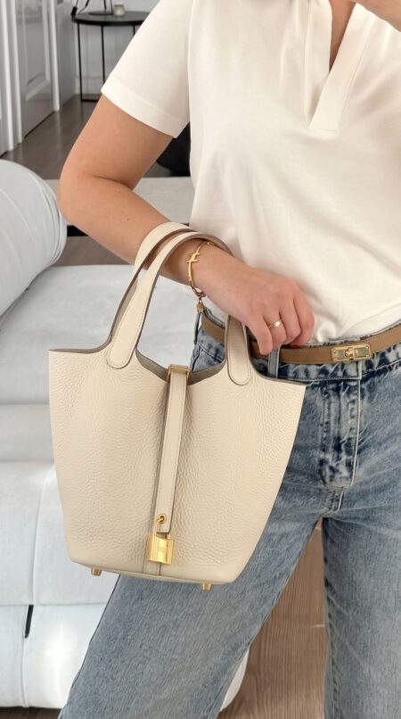 Model carrying the Herme$ Taurillon Clemence Picotin Lock 18 PM in Béton with gold hardware