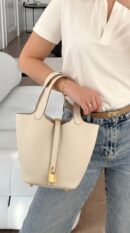 Model carrying the Herme$ Taurillon Clemence Picotin Lock 18 PM in Béton with gold hardware