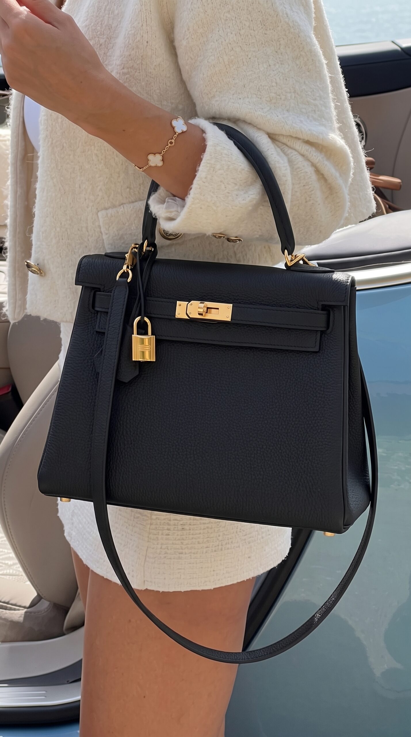 Model carrying the Herme$ Black Togo Leather Kelly Retourne 25 with gold hardware