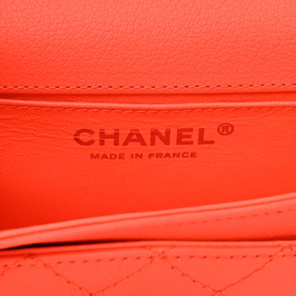 Close-up of the silver-tone chain and flap hardware on the vibrant orange Ch@nel Reissue Belt Bag