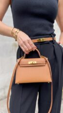 Model carrying the brown Herme$ Mini Kelly Sellier Touch 20 with adjustable shoulder strap