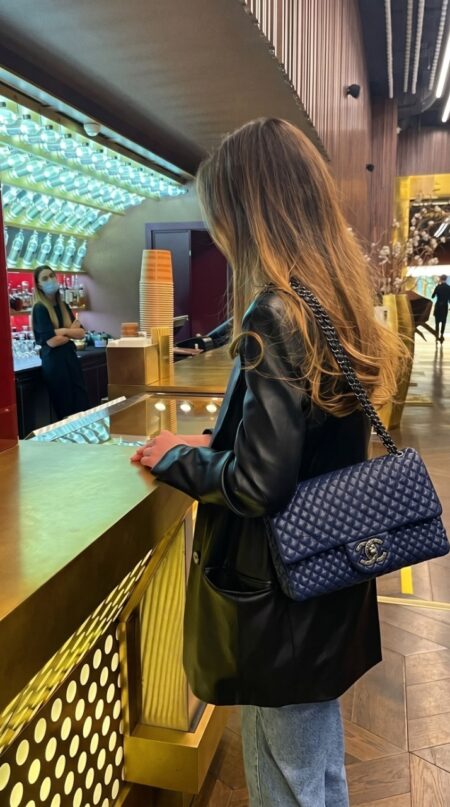 Model wearing the navy Ch@nel Small Flap Bag with leather-threaded chain strap