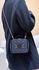 Model carrying the navy Ch@nel Filigree Vanity Case with gold-tone chain strap