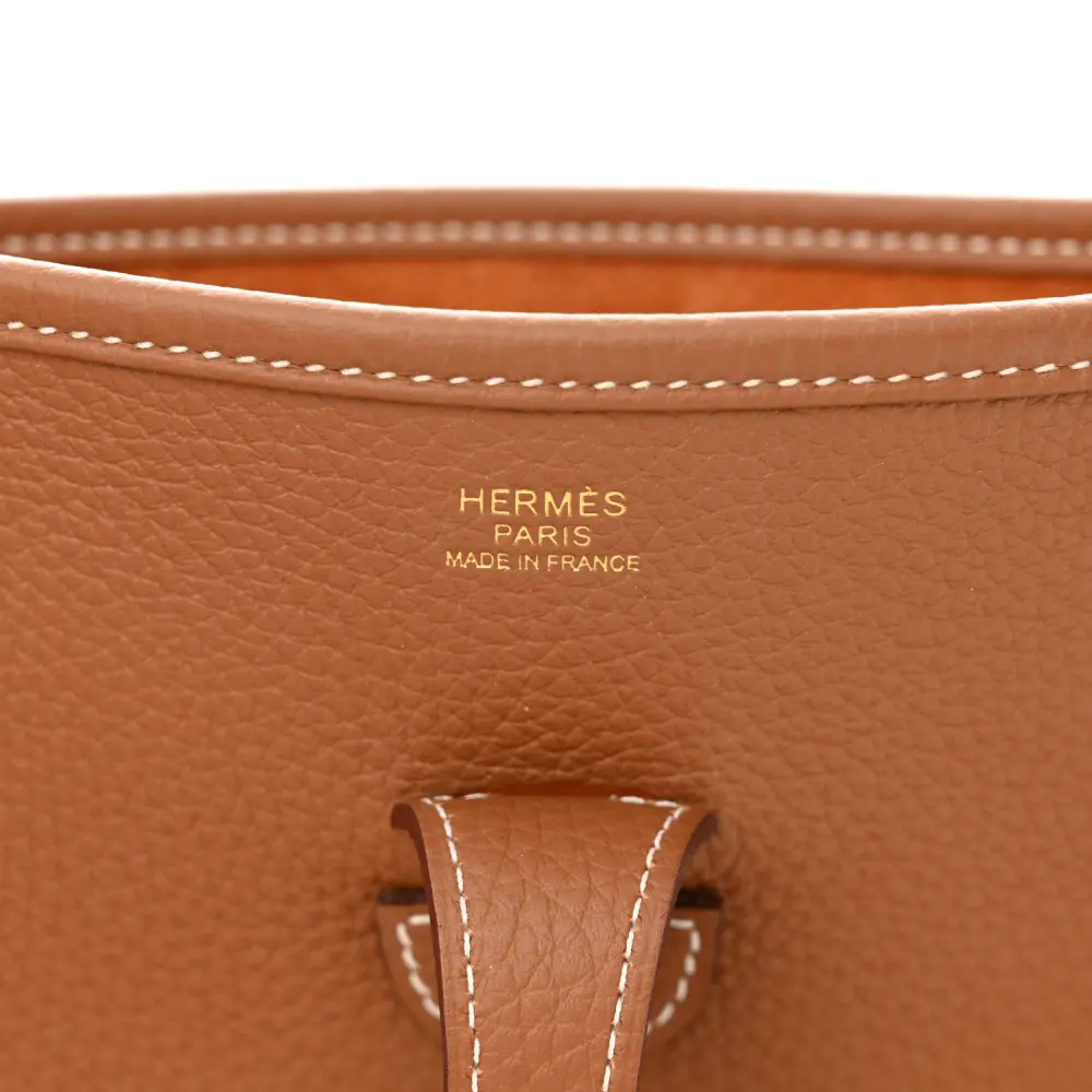Close-up of the perforated front motif and refined hardware on the brown Herme$ Evelyne III PM