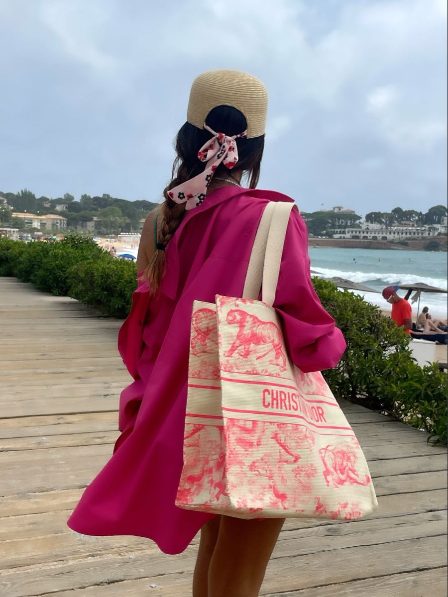 Model carrying the natural straw D!0r Dioriviera Tote with intricate red design