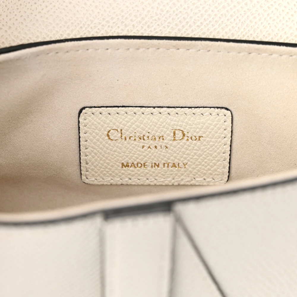 Close-up of the brass-tone accents and curved flap detailing on the white Saddle Bag