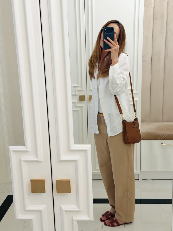 Model carrying the brown Taurillon Clemence Herme$ Evelyne TPM crossbody bag