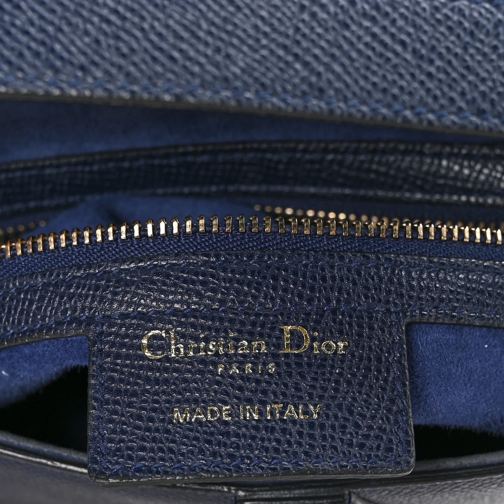Close-up of the signature D-shaped hardware and refined details on the navy blue Saddle Bag
