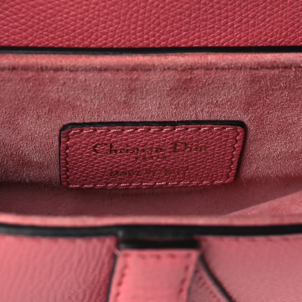 Close-up of the magnetic D stirrup clasp on the pink grained calfskin Mini Saddle Bag