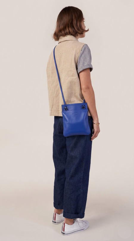 Model carrying the Bleu Electrique Herme$ Mini Aline crossbody bag