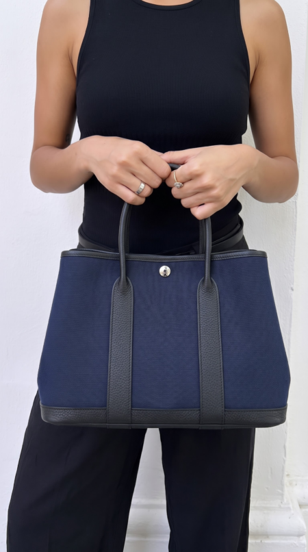 Model carrying the Bleu Marine and Black Herme$ Garden Party 30 tote