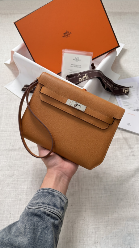 Model carrying the brown Epsom Herme$ Kelly Dépêches 25 Pouch