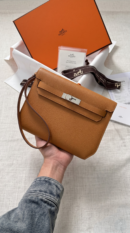 Model carrying the brown Epsom Herme$ Kelly Dépêches 25 Pouch