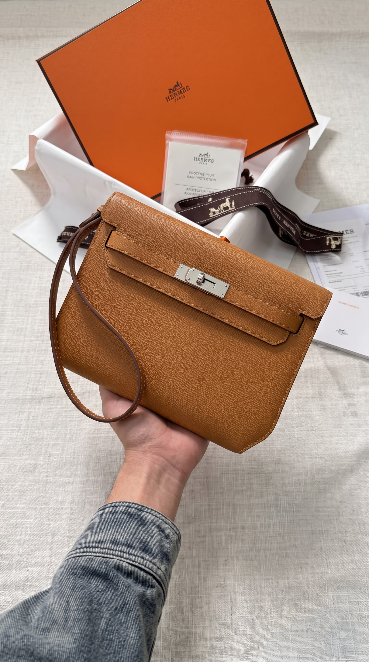 Model carrying the brown Epsom Herme$ Kelly Dépêches 25 Pouch