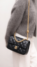 Model carrying the black Ch@nel Small Pillow Crush Flap with gold-tone chain shoulder strap