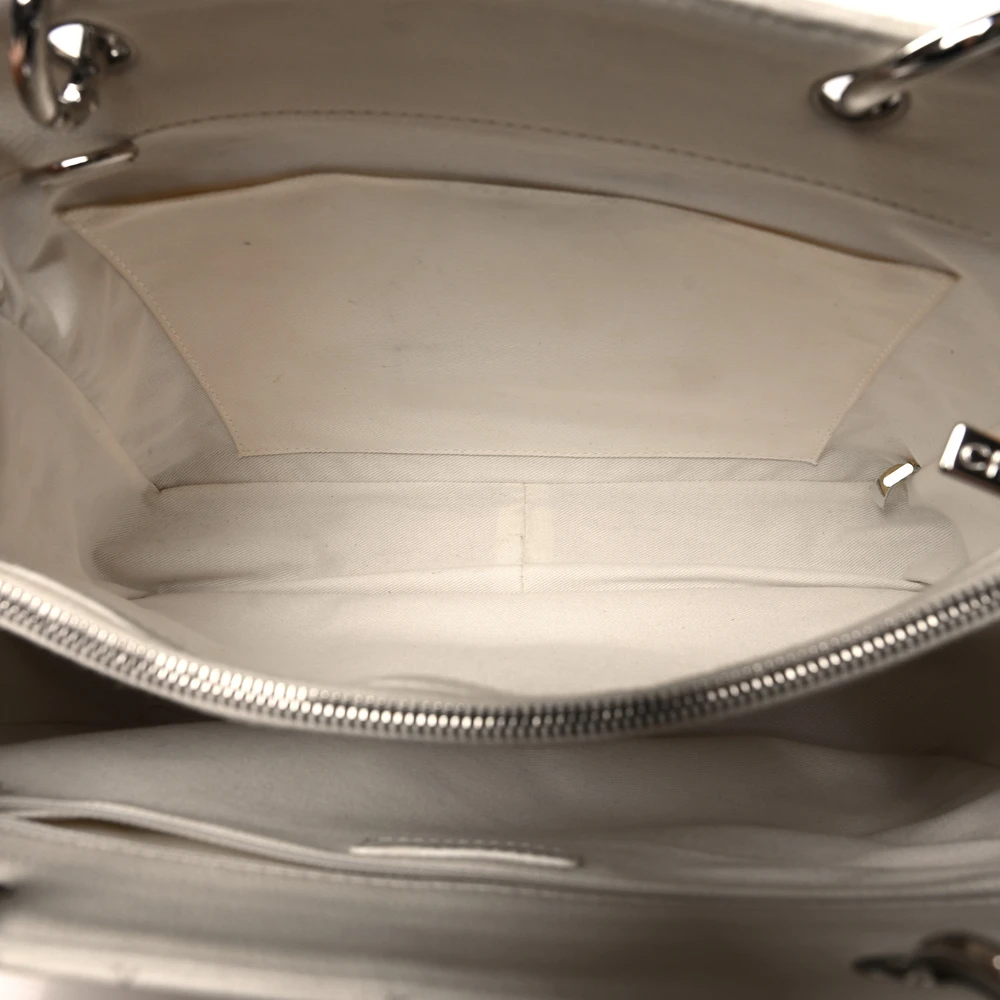 Interior view of the white Ch@nel Grand Shopping Tote showing its partitioned compartments, zipper compartments, and patch pockets