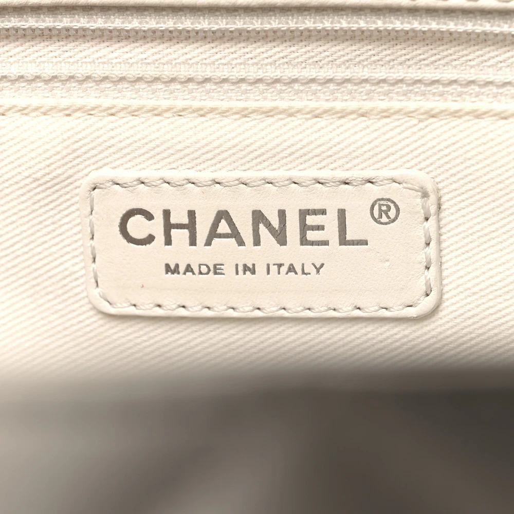 Close-up of the stitched CC logo and silver-tone chain hardware on the white Ch@nel Grand Shopping Tote
