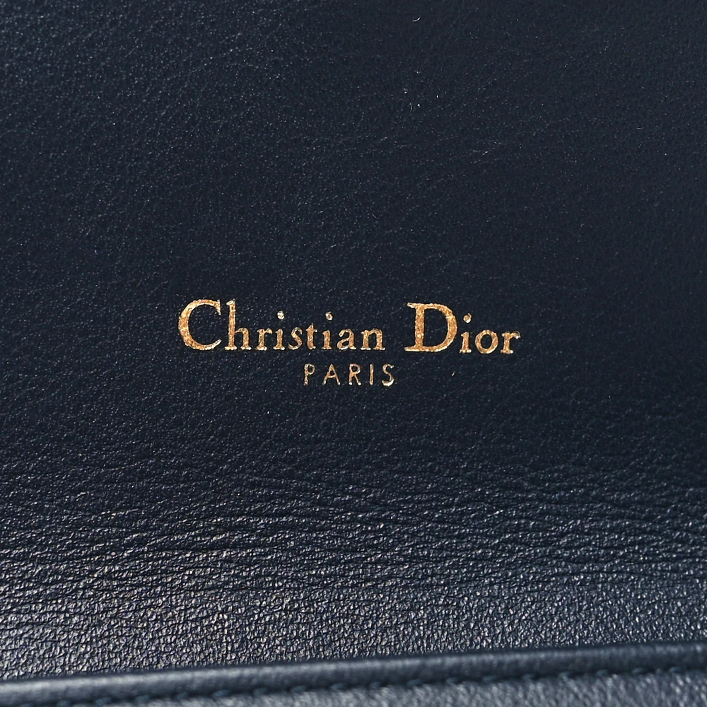 Close-up of the brass D charm, Saddle-style flap, and chain strap on the D!0r Saddle Chain Long Wallet