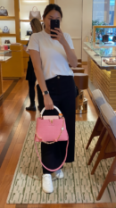 Model carrying the vibrant pink Lou!S Vuiton Capucines Mini with gold-tone chain strap