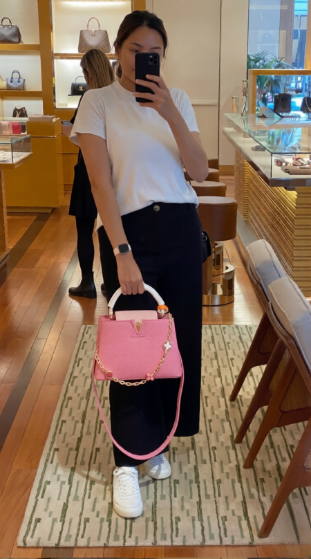 Model carrying the vibrant pink Lou!S Vuiton Capucines Mini with gold-tone chain strap
