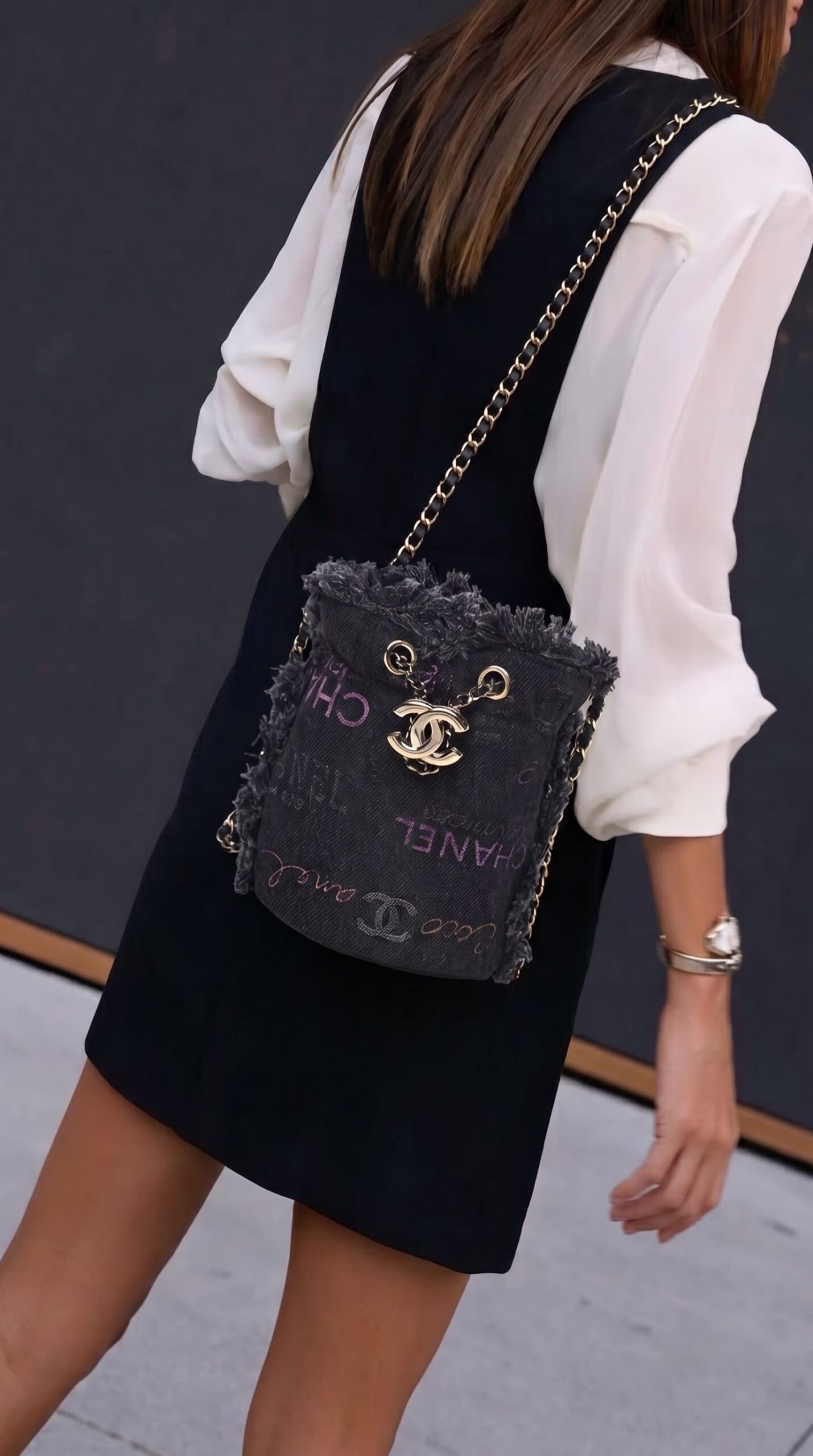 Model carrying the black denim Ch@nel Mood Mini Bucket Bag with chain shoulder strap